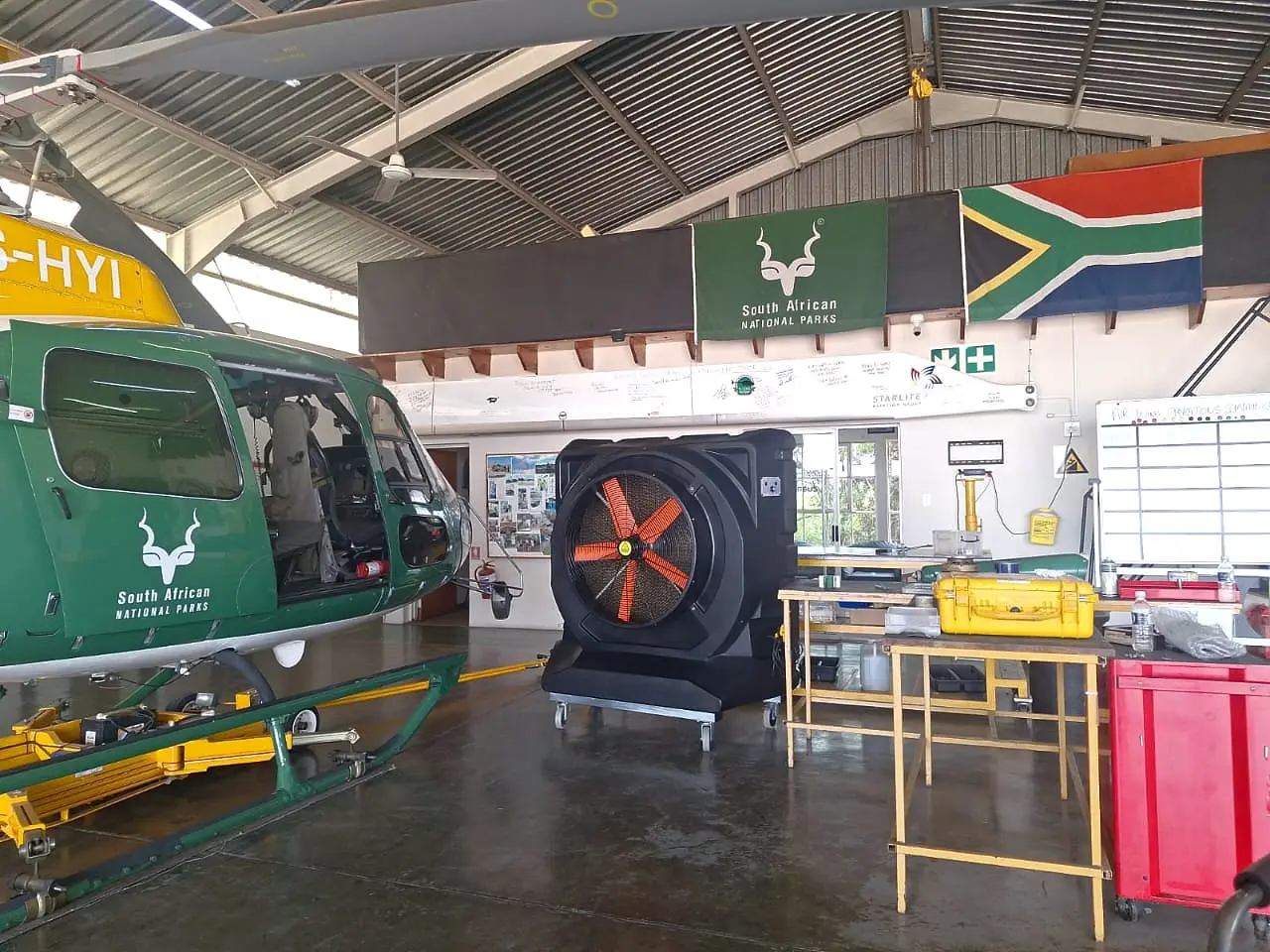 MaxCool Omega mobile evaporative cooler beside a SANParks helicopter in an aviation hangar in South Africa.